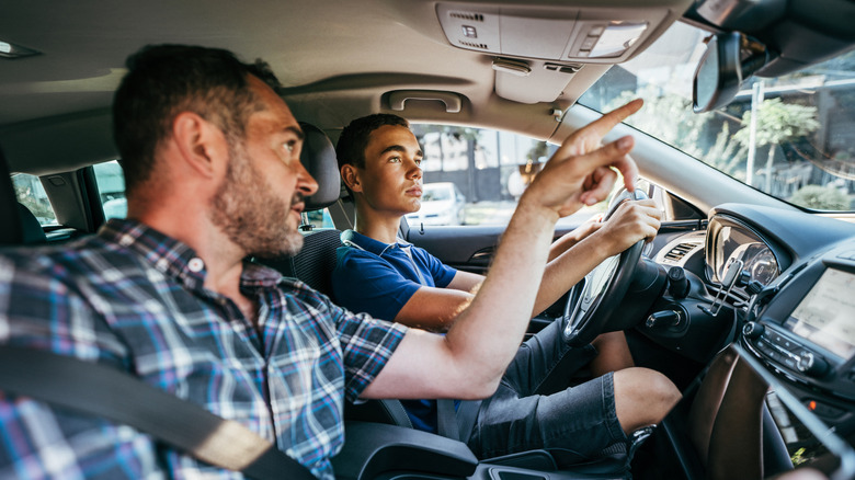 A teen driver with an adult passenger helping teach him road rules