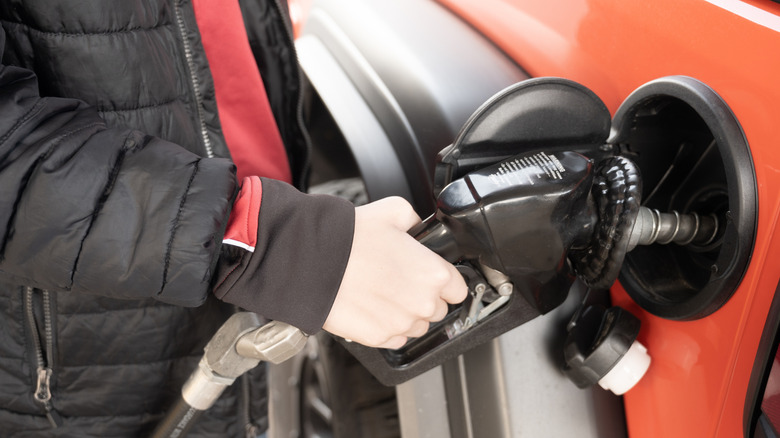 A young driver filling up with fuel at a gas station