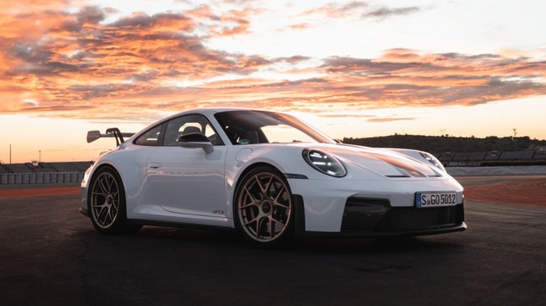 A white Porsche 911 GT3 with the Weissach Package parked at sunset