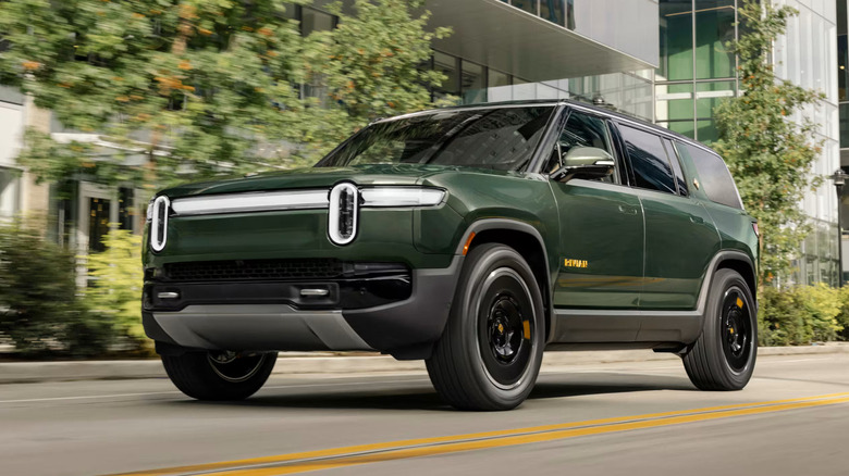 A Rivian R1S driving down a city street.