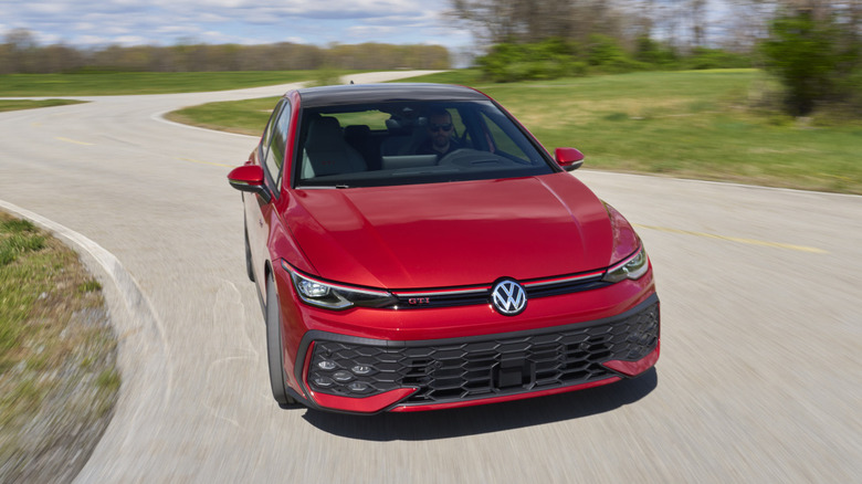 A red 2025 Volkswagen GTI driving down a country road.