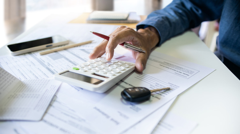 Close up of car dealer hand working on calculator