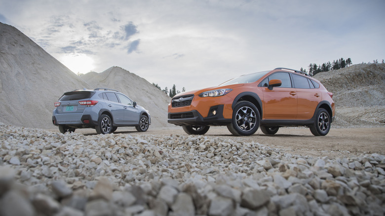 A gray 2019 Subaru Crosstrek Limited and an orange 2019 Crosstrek Premium parked in gravel yard
