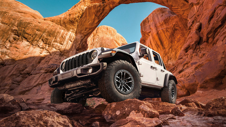 Low front 3/4 of a white 2026 Jeep Wrangler on rocks.
