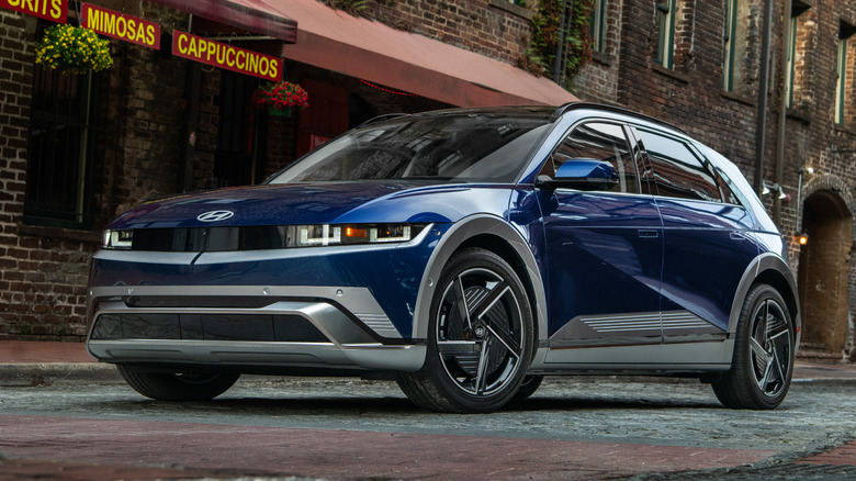A blue Hyundai Ioniq 5 on a road near a cafe.