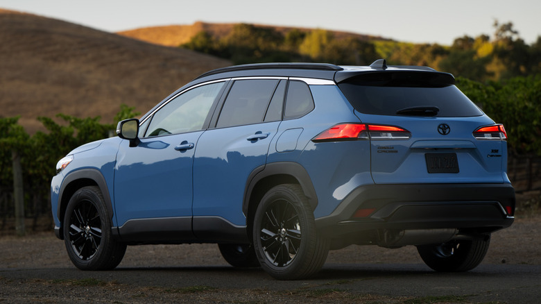 A blue Toyota Corolla Cross Hybrid parked with mountains in the background