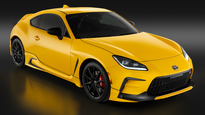 A yellow Yuzu Edition Toyota GR86 on a dark surface.