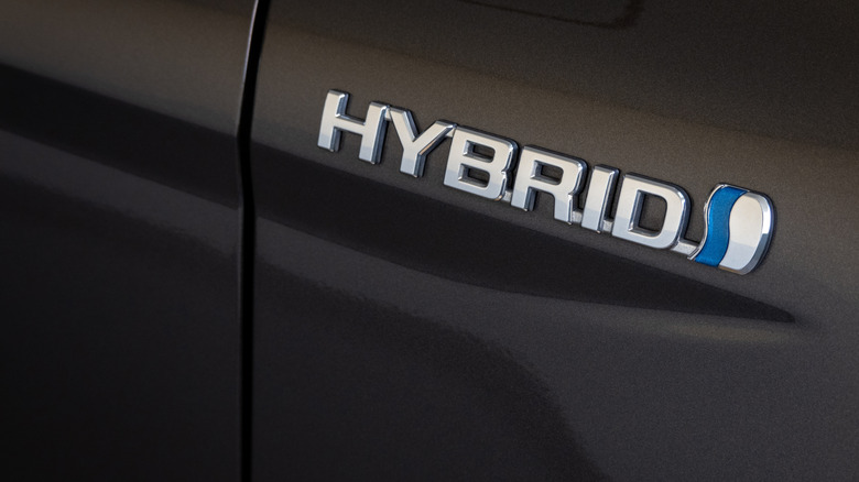 A "hybrid" badge on the panel of a gray car that has a traditional hybrid powertrain.