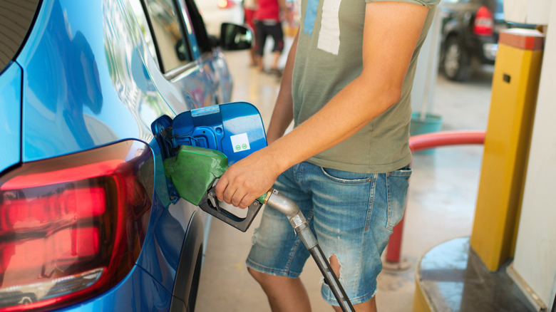 A person filling up a car with gas at a fuel station