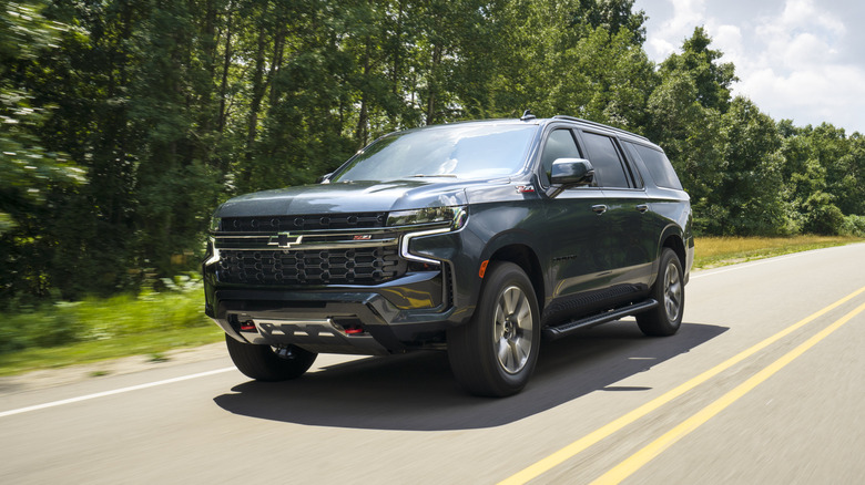 A black 2021 Chevrolet Suburban in motion on a two-lane road.