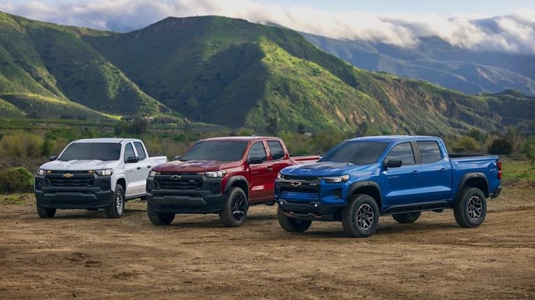 Three 2025 Chevrolet Colorado models on a hilltop, one each in white, red, and blue.