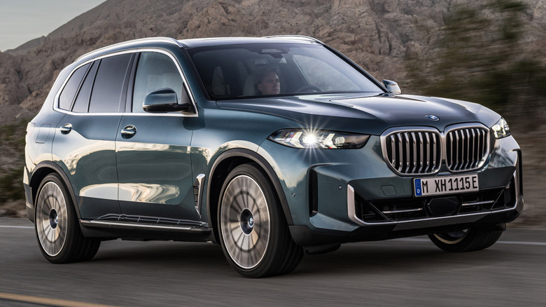 A BMW X5 on a road in front of mountains