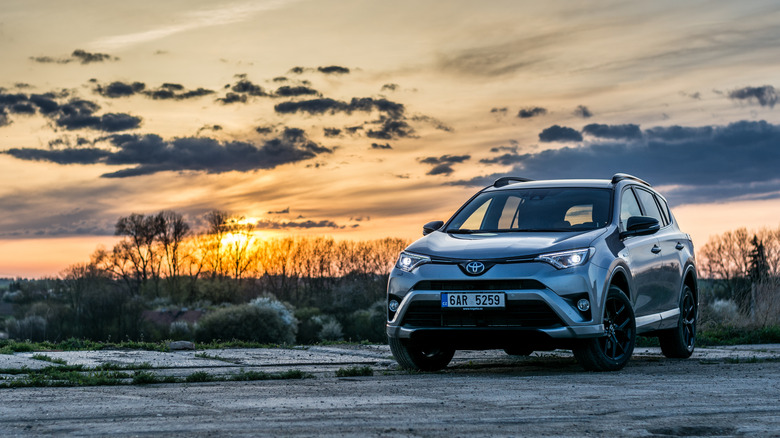 2018 Toyota RAV4 Hybrid parking on a concrete lot in the sunset.