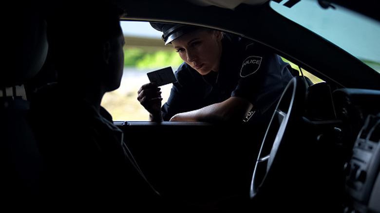 Inside view of a car with a police woman looking at the driver's license in the window