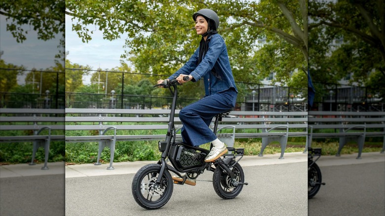 A person riding a Jetson Bolt Pro Max Electric Bike in front of a park bench with tennis courts in the background