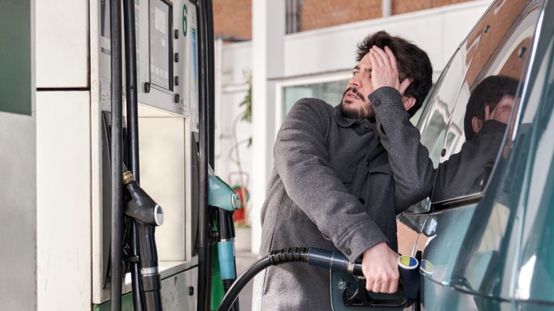 Unhappy man filling his vehicle's gas tank