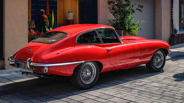 A 4.2 red Jaguar E-Type parked outside.