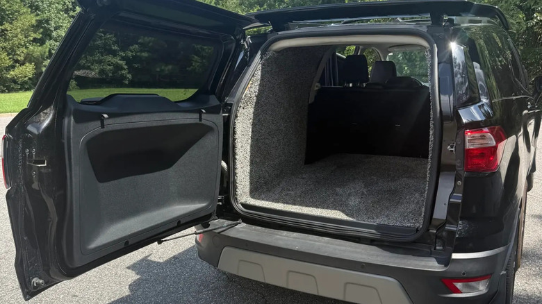 A photo of the shag-lined trunk of the black EcoSport with green grass and trees visible in the background