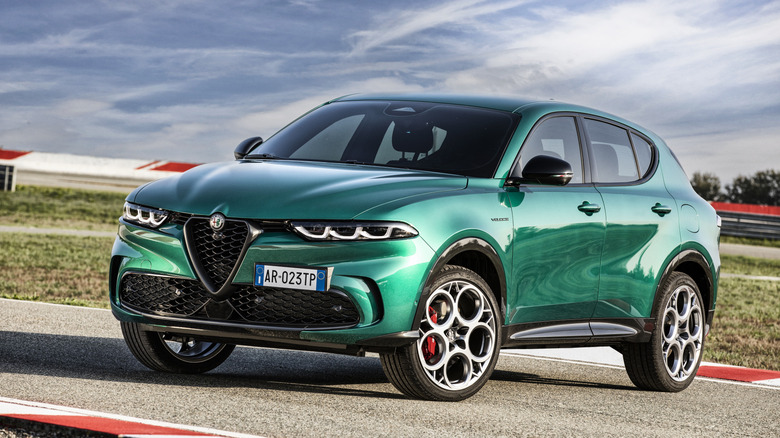A green Tonale parked on a race track in front of grass and a cloudy blue sky
