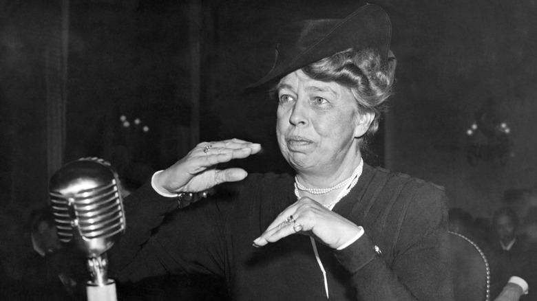 Eleanor Roosevelt gestures to another person while speaking into a microphone