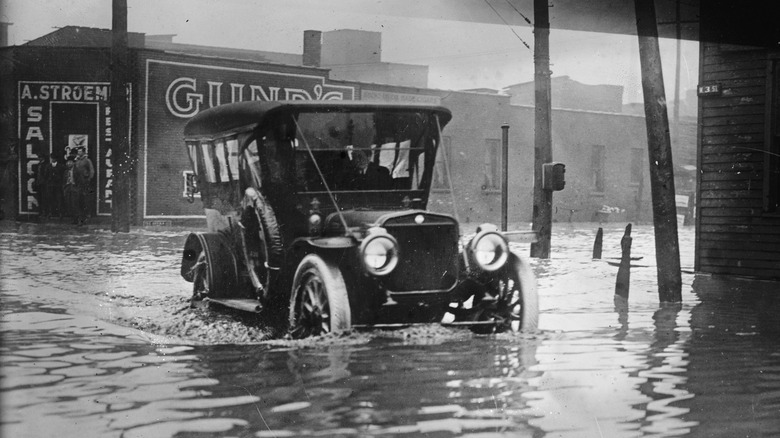 A black and white photo of a Ford Model T in cleveland during a flood. the floodwater is halfway up the car's wheels.