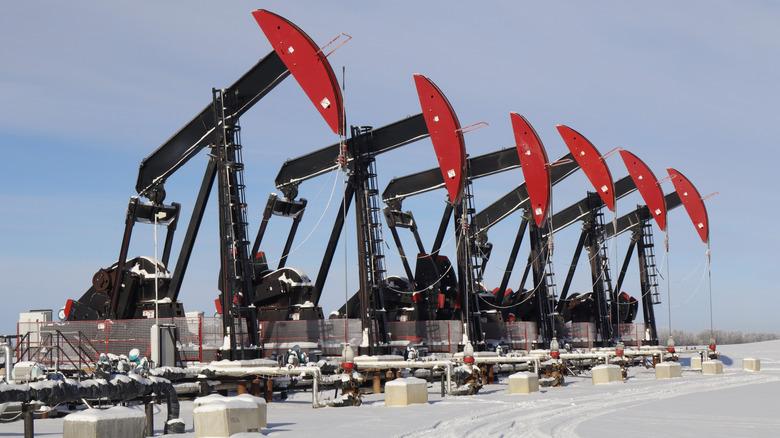 A row of six oil pumps for oil wells in the winter