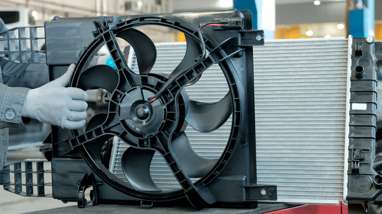 A mechanic test-fitting the shroud and cooling fan on a new radiator.