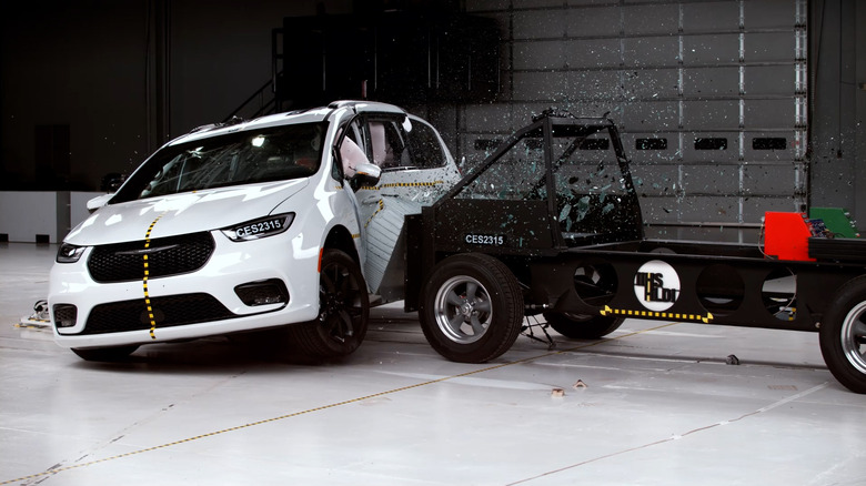 A white van is struck by a crash testing rig in a side impact scenario.