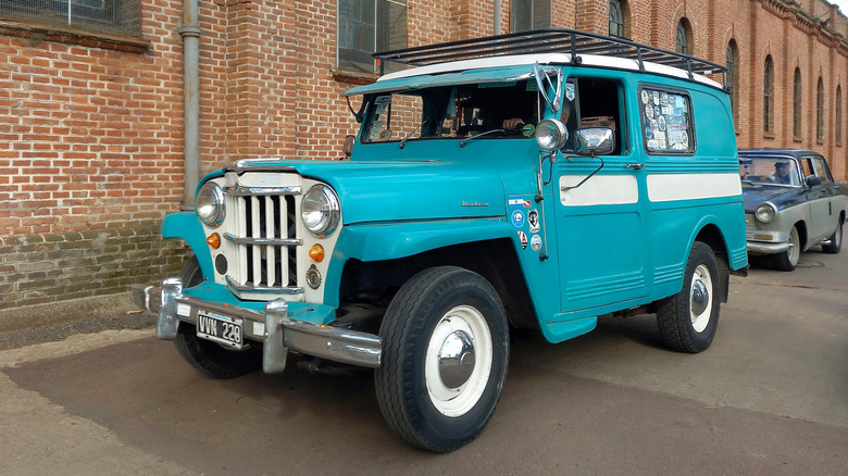 A blue Jeep Overland Station Wagon parked beside a brick building