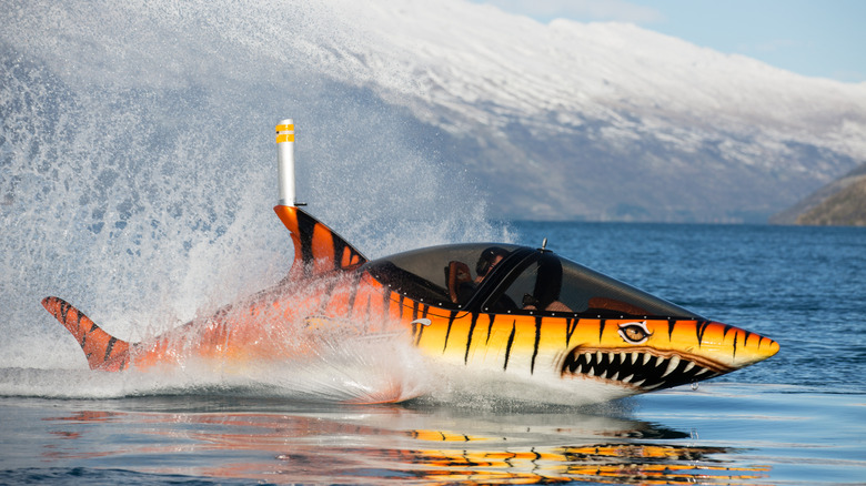 The Seabreacher X or shark model painted as a tiger...that's a shark in orange, skims across the water with snowy mountains in the background.
