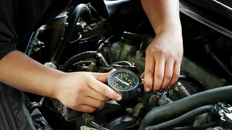 Mechanic checks the compression of cylinders on an engine.