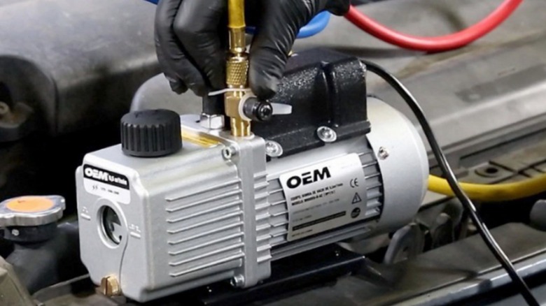 A close-up image of an OEM branded automotive vacuum pump being used in a car's engine bay