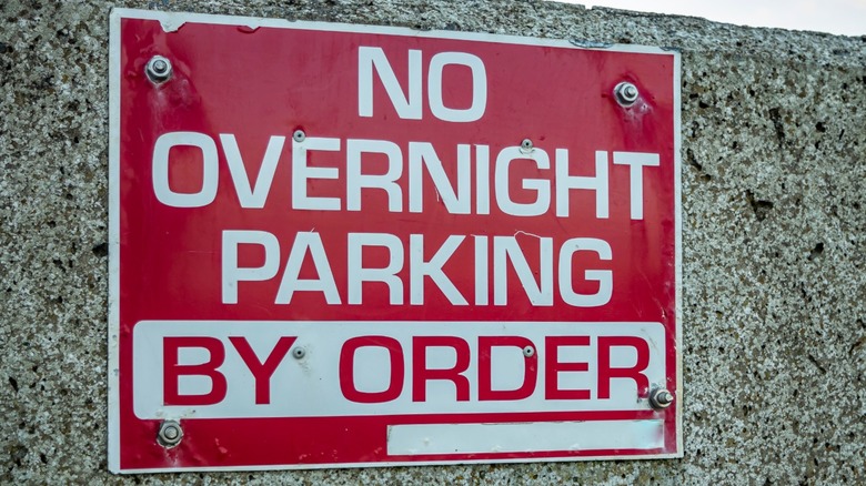 Red motion pinch achromatic letters that says "no overnight parking"