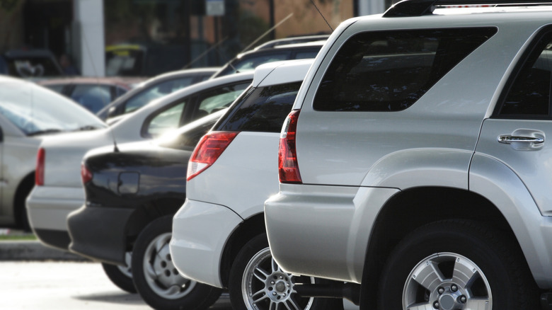 A row of silver, white and black vehicles in a hot parking lot