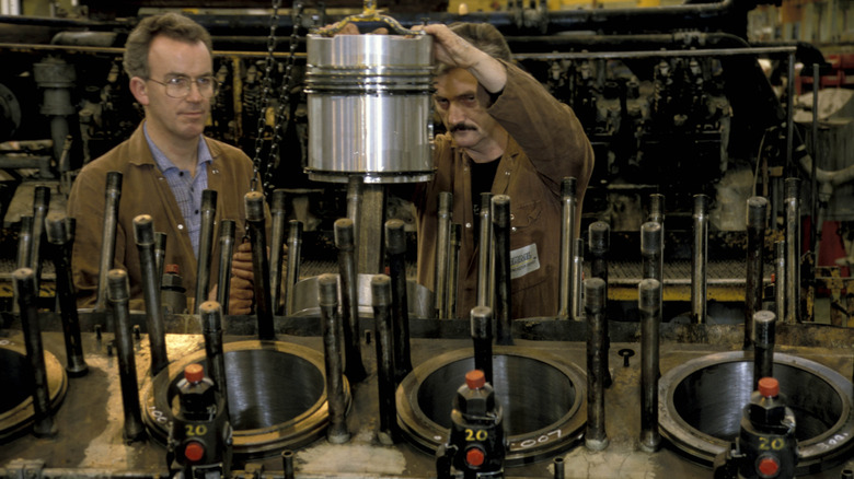 Engineers fit a new piston during engine refurbishment in Doncaster, UK, circa 1993
