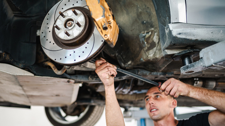 A mechanic checking the underside of a car and the steering