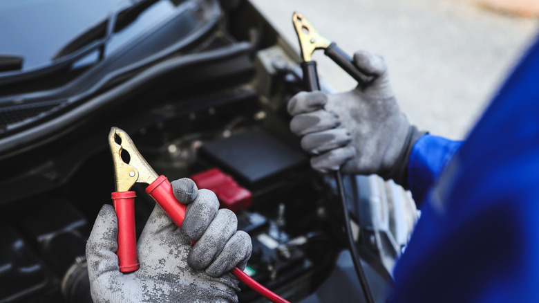 Man holding jumper cables to jump start a car