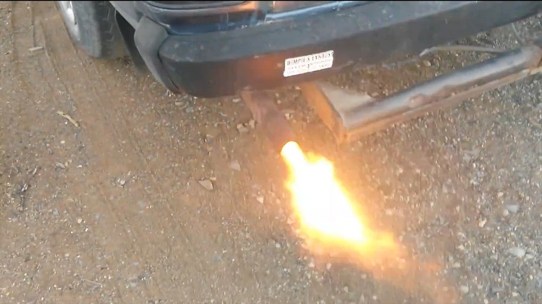 An old car backfiring with a flame out of the tailpipe