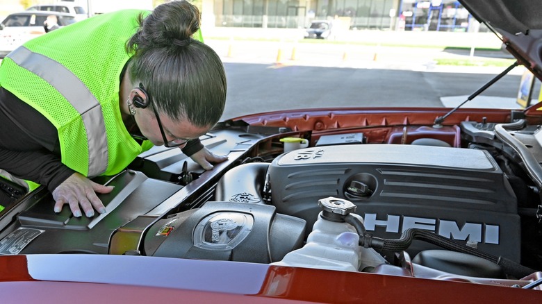 A lady checking out the modern Hemi engine in a Dodge Challenger.