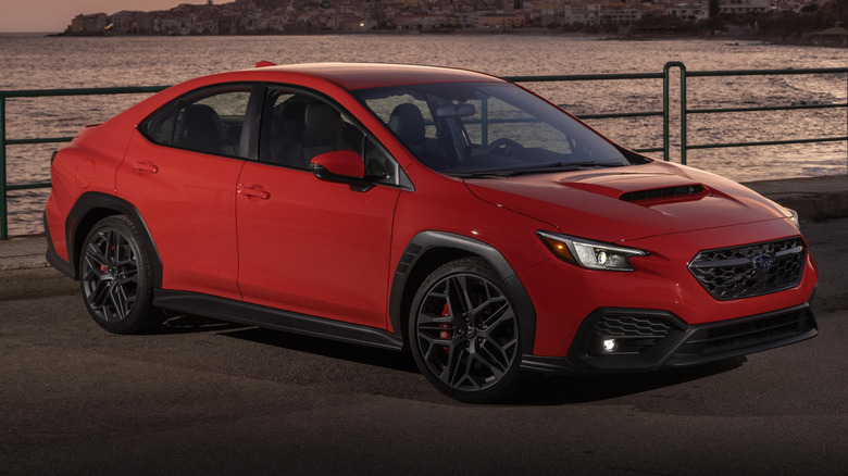 A red Subaru WRX parked next to the ocean