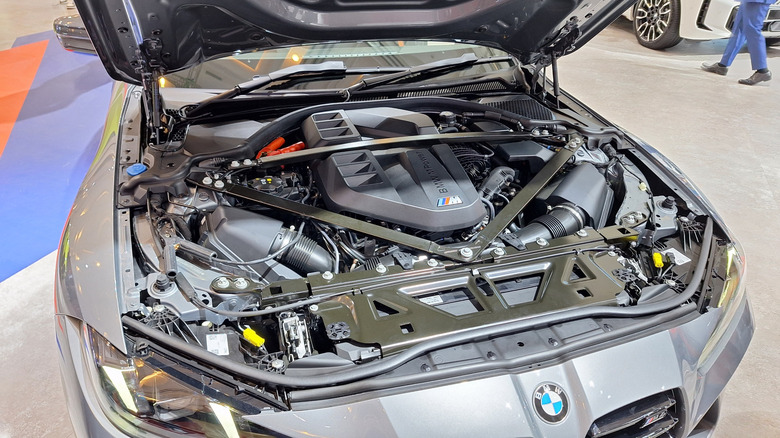 A BMW M4 with its hood open, showcasing its S58 engine.