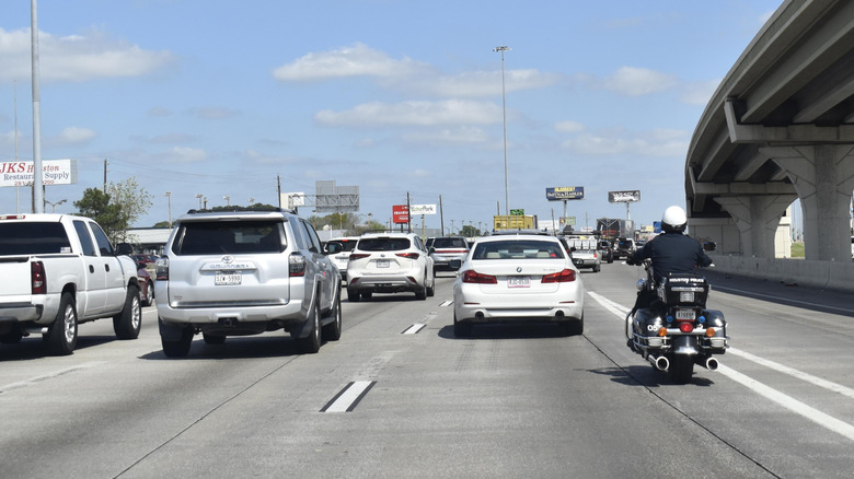 A police highway patrol motorcycle in traffic on a three-lane highway.