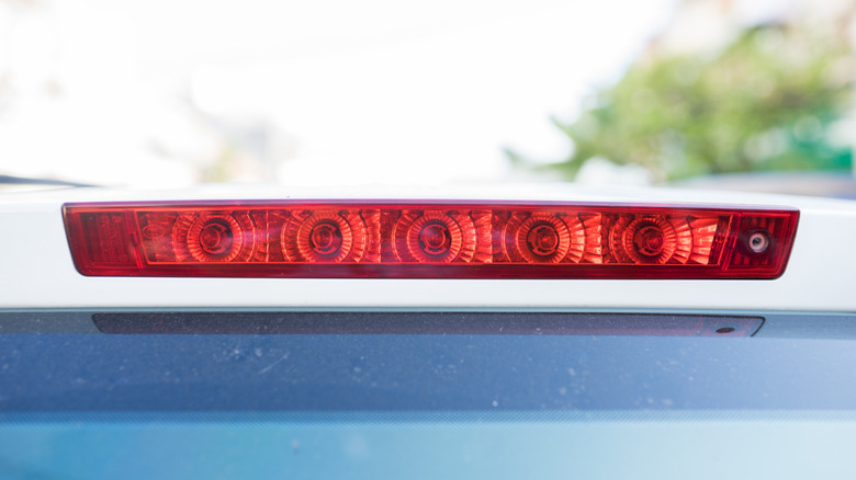 A close-up of a white car's rear center brake light.