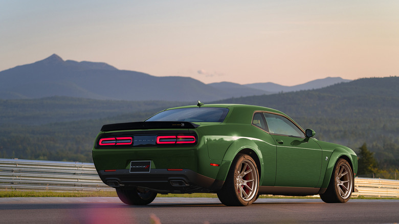 A 2023 Dodge Challenger Scat Pack Wide Body Swinger in dark green at sunset