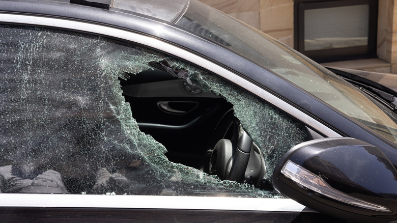 A dark blue Mercedes sedan with a broken front passenger-side window.