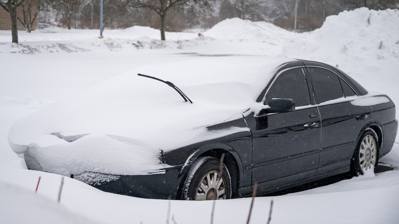 A car buried in snow with its windshield wiper sticking out