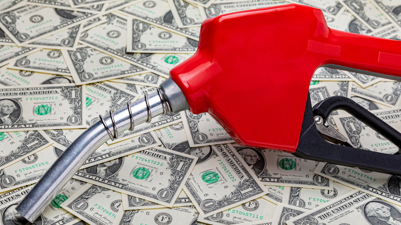 Photo of a fuel nozzle atop one dollar bills