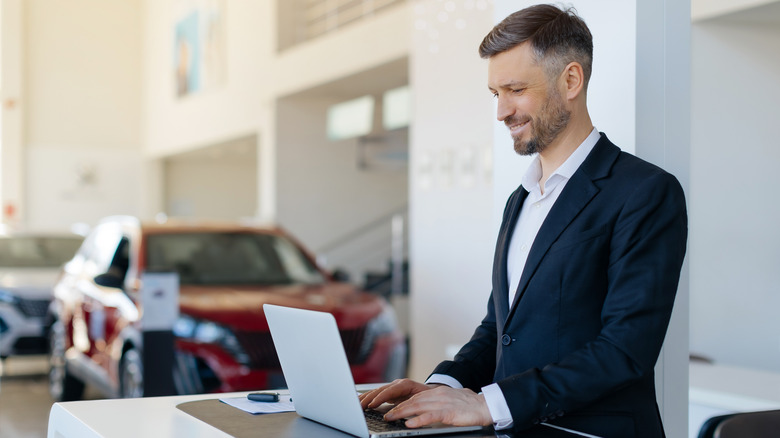 A man using a laptop computer at a dealership.