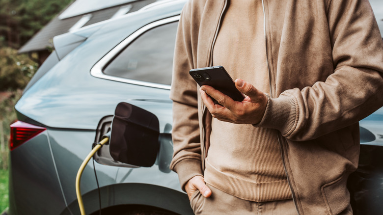 A person checking the charge level of their EV using an app on their smartphone