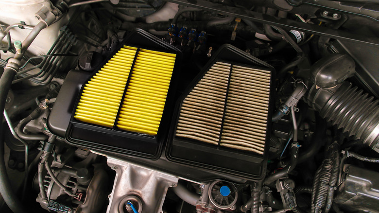 A new and used air filter placed on top of an engine cover